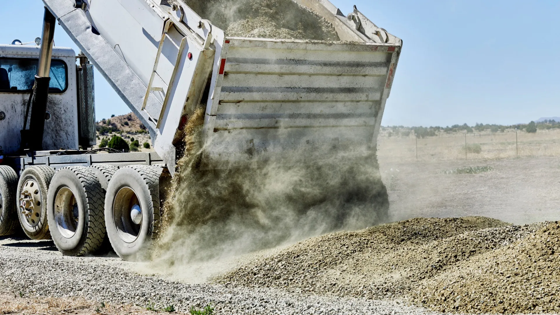 Dump truck unloading fill dirt at a site